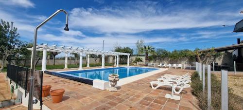 una piscina con sillas blancas y una valla en Casa en el corazón de Córdoba, en Montoro