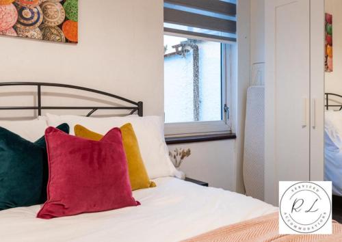 een slaapkamer met een bed met kleurrijke kussens bij Modern Apartment in Wigston with Free Parking! in Wigston Magna
