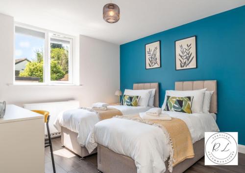 2 camas en una habitación con paredes azules en Comfy Modern 2 Bed near Glenfield Hospital, sleeps up to 6 en Glenfield