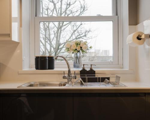 a kitchen sink with a window and a vase of flowers at Windsor Court in Brighton & Hove