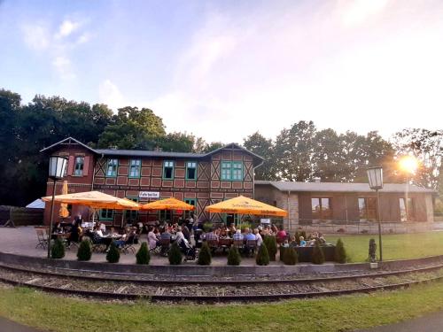 a group of people sitting at tables in front of a building at Pension und Appartements alter Fehrbelliner Bahnhof in Fehrbellin