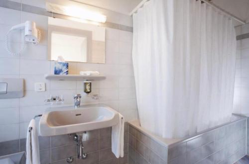 uma casa de banho com um lavatório e uma cortina de chuveiro em FriendsHouse Appenzellerhof em Speicher