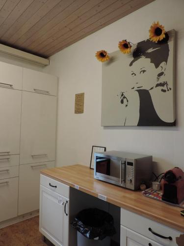 a kitchen with a counter with a microwave and flowers on the wall at FriendsHouse Appenzellerhof in Speicher