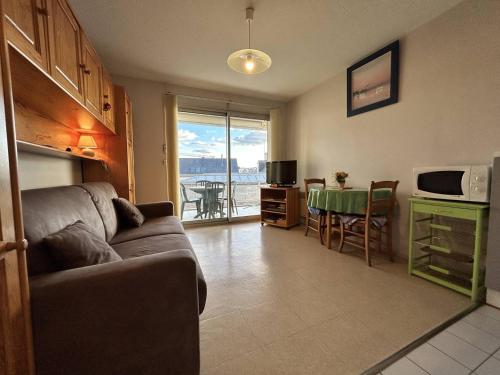 un salon avec un canapé et une cuisine avec une table dans l'établissement 537 - Studio les pieds dans l'eau, en bordure de la plage du centre d'Erquy, à Erquy