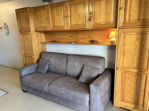 um sofá numa sala de estar com armários de madeira em 537 - Studio les pieds dans l'eau, en bordure de la plage du centre d'Erquy em Erquy