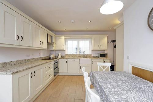 una cocina con armarios blancos y una mesa con sillas. en Royal Hillsborough Village Luxury Townhouse, en Hillsborough