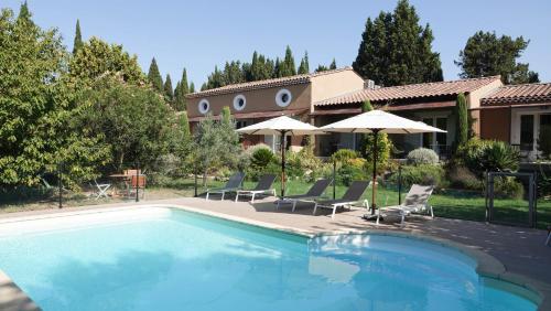 - une piscine avec des chaises et des parasols à côté d'une maison dans l'établissement Mas des Marguerites, à Maussane-les-Alpilles