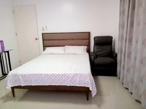 a bedroom with a bed and a chair at Casita de Zacate in Cagayan de Oro