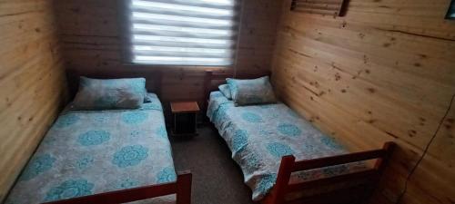 a room with two beds in a cabin with a window at Casa independiente en Futrono in Futrono