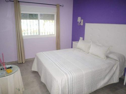 1 dormitorio con cama blanca y paredes moradas en Hostal Restaurante La Ilusion, en El Palmar
