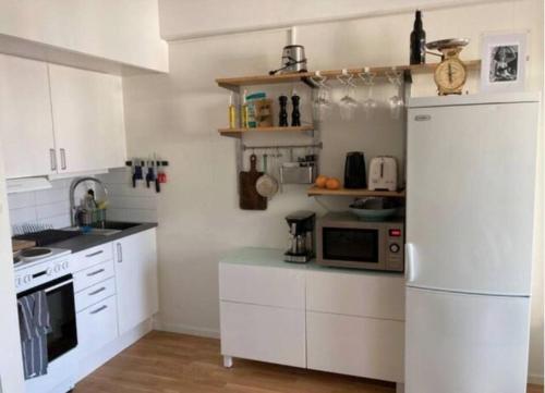 a kitchen with white cabinets and a white refrigerator at Malmö innerstad in Malmö