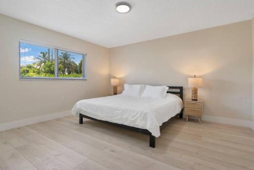 een witte slaapkamer met een bed en een raam bij Unit 4 Spacious 1 bedroom Apartment with 70inch smart TV in Fort Lauderdale