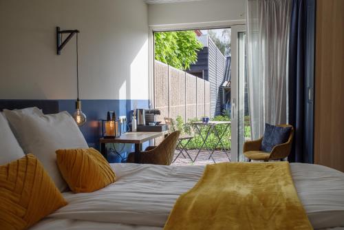 a bedroom with a bed and a view of a patio at Hotel De Zilte Zeeuw in Kortgene