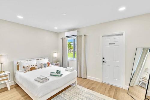 een witte slaapkamer met een bed en een spiegel bij 1 bedroom tropical pool house in Hallandale Beach