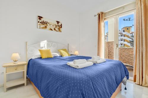 Un dormitorio con una cama azul con toallas. en Golondrina by IVI Real Estate, en Torremolinos