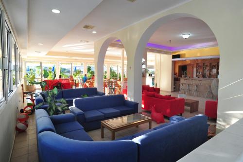 a lobby with blue couches and red chairs at Metaxa Hotel in Kalamaki