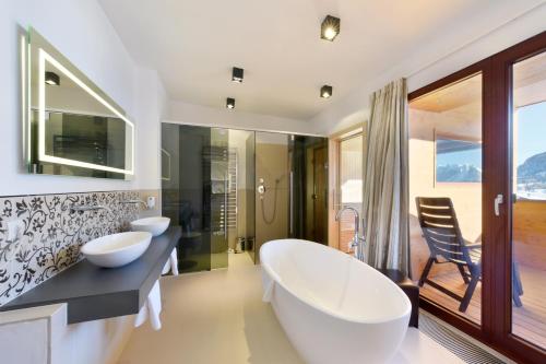 a bathroom with two sinks and a large tub at Mountains Hotel in Seefeld in Tirol