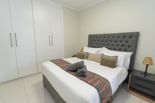 una camera da letto con un grande letto bianco con testiera grigia di Hallack Du Parc Modern Living a Port Elizabeth