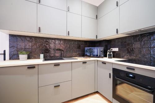 une cuisine avec des armoires blanches et un appareil noir dans l'établissement Parisuites Central Grands boulevards Chic Folies Bergères, à Paris