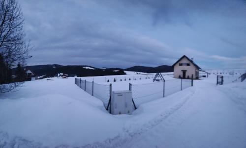 ein mit Schnee bedeckter Zaun neben einem Haus in der Unterkunft BliżejGorców in Lubomierz