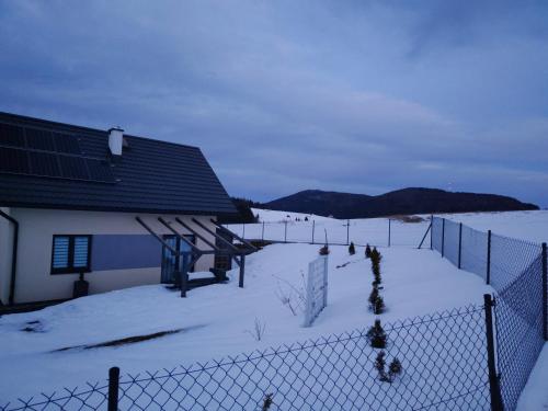 Ein Zaun im Schnee neben einem Gebäude in der Unterkunft BliżejGorców in Lubomierz