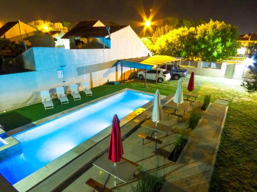 a swimming pool with umbrellas and chairs next to a house at Alquileres Relax11sanclemente in San Clemente del Tuyú