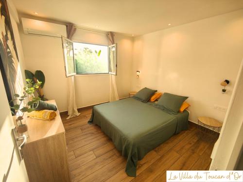 a bedroom with a green bed and a window at La Villa du Toucan d'Or, au cœur de la Guadeloupe in Petit-Bourg