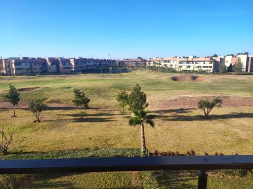 Blick auf ein Feld mit Palmen und Gebäuden in der Unterkunft Appartement Golf City Prestigia Marrakech in Marrakesch