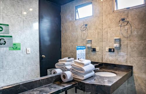 a bathroom with a pile of towels on a counter at Hotel Santa Barbara Real in Bogotá