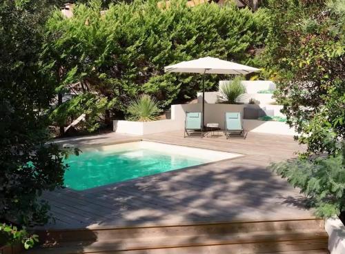 une piscine avec deux chaises et un parasol dans l'établissement Villa Piladi, à Lacanau