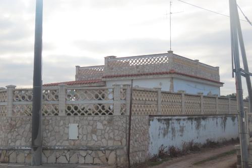 Ein Steinzaun mit einem Gebäude dahinter. in der Unterkunft California in Bari