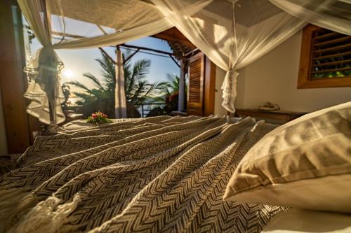 a bedroom with a large bed with a view of a palm tree at Komba Cabana in Nosy Komba