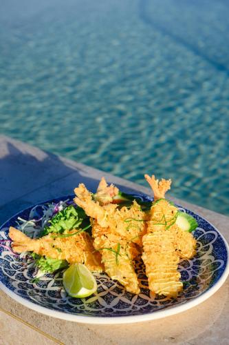 a plate of food on a table next to the water at XVI Suites - Adults Only in Naxxar