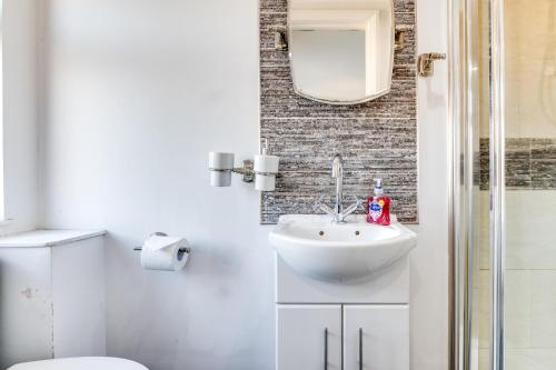 uma casa de banho com um lavatório, um WC e um espelho. em LiveStay - Stylish 3-Bed Gem in Trendy E1 London em Londres