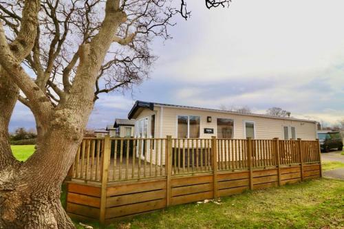 a house with a fence and a tree at Warren Haven in Dawlish Warren