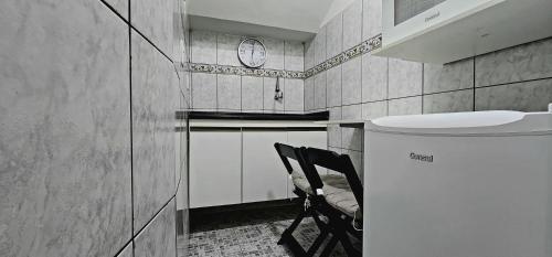 a kitchen with a chair and a clock on the wall at Apart Hotel Farol de Itapuã - Suíte com cozinha compacta à 250m da praia e farol de Itapuã in Salvador