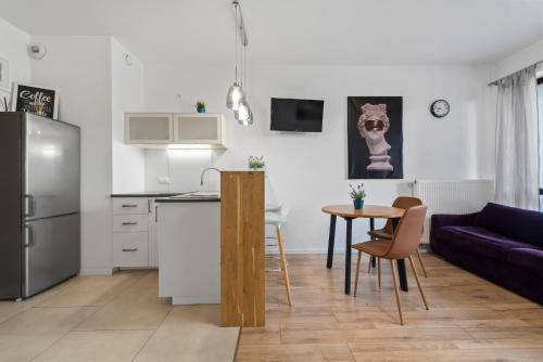 een keuken en een woonkamer met een tafel en een paarse bank bij Comfy studio. City center. in Warschau