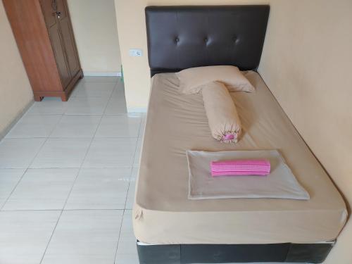 Una cama con una almohada rosa encima. en Serasikost en Sukarami