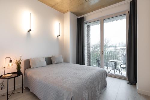 1 dormitorio con cama y ventana grande en Bossa Nova - modern 2 bedroom apartment in the center, en Vilna