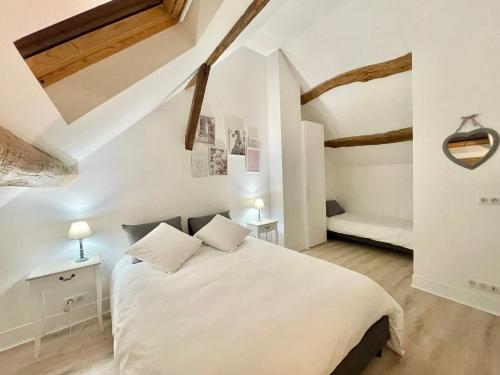 a bedroom with a white bed and wooden ceilings at La Demeure des Hôtes 10 minutes de Disney in Couilly-Pont-aux-Dames
