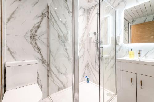 a white bathroom with a shower and a toilet at Livestay Stylish 1-Bed Apartment in Stratford in London
