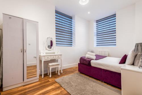 a bedroom with a bed and a dressing table and a mirror at Livestay Stylish 1-Bed Apartment in Stratford in London