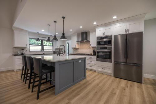a kitchen with white cabinets and a stainless steel refrigerator at Mid-century Modern Impeccable Remodel with Hot Tub in Asheville
