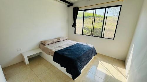 a small bedroom with a bed and a window at Piedras del Sol Casa Campestre in Guaduas
