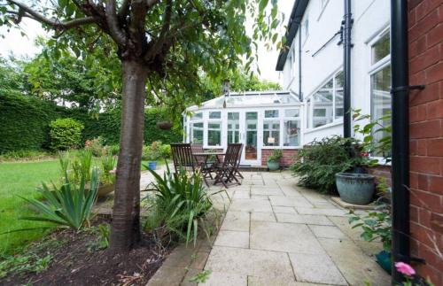 een patio met stoelen en een glazen huis bij Serene 4BR House with Garden & Conservatory in Nottingham