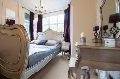a bedroom with a bed and a table and a mirror at Serene 4BR House with Garden & Conservatory in Nottingham