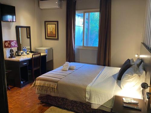 a bedroom with a bed and a desk and a window at HOTEL RESIDENCIAL CITY in Maputo