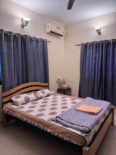 1 dormitorio con 1 cama con cortinas azules en Villa Almeida, en Panaji