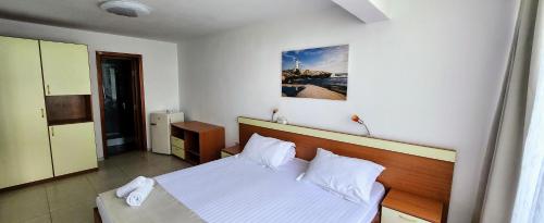 Schlafzimmer mit einem Bett mit weißer Bettwäsche und Kissen in der Unterkunft Vila Aqua in Eforie Sud