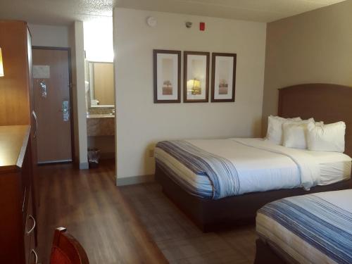 a hotel room with two beds and a bathroom at AmericInn by Wyndham Dickinson in Dickinson